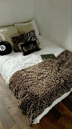 a leopard print comforter on a bed in a room with wood floors and white walls