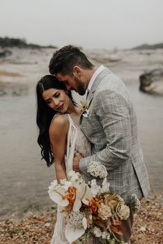 a man and woman standing next to each other in front of a body of water