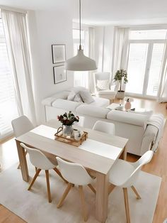 a living room and dining area with white furniture in the center, large windows on both sides