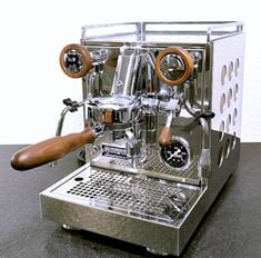 an espresso machine sitting on top of a counter next to a wooden handle