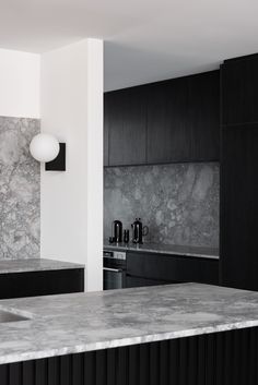 a kitchen with marble counter tops and black cabinets