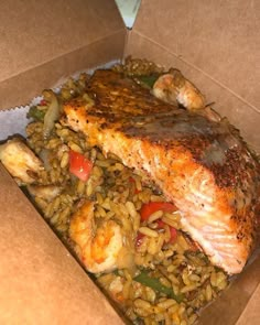 a box with some fish and rice in it on the table next to a fork