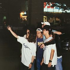 three young men standing next to each other in front of a building at night time