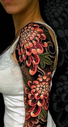 a woman's arm with flowers on it and an orange flower in the middle