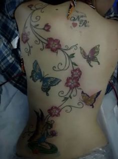 a woman's back with butterflies and flowers on it