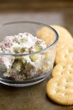 a glass bowl filled with food next to crackers