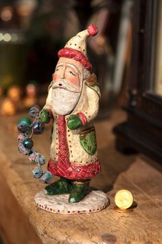 a figurine of a santa clause holding a christmas ornament on a table