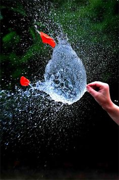 a hand holding an object with water splashing out of it