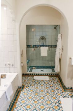 a bathroom with blue and yellow tile on the floor, shower stall and sink area