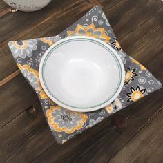 a white bowl sitting on top of a gray and yellow napkin