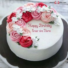 a white cake with pink and red flowers on it's top is sitting on a plate