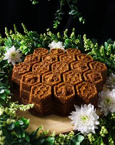 some kind of cake sitting on top of a cutting board surrounded by flowers and greenery