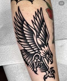 a black and white eagle tattoo on the arm, with an apple in the background