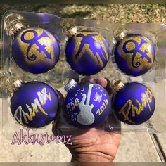 six purple and gold ornaments in a plastic package