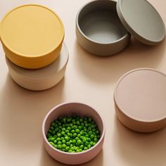 three bowls with peas in them sitting on a table next to another bowl and container