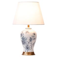 a white and blue vase with a light on it's side next to a lamp