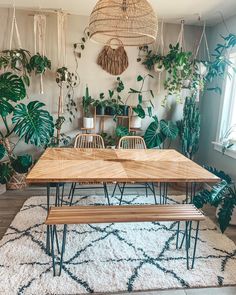 a dining room table and bench in front of plants