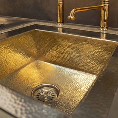 a metallic sink with gold faucet and two brass faucets