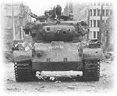 an old photo of a tank with soldiers sitting on it's turrets in the street