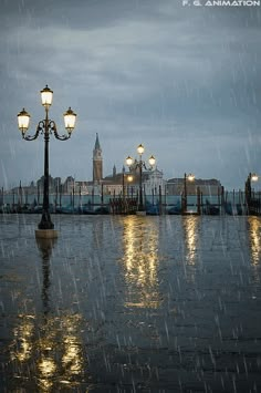 a street light sitting in the middle of a rain soaked walkway with lights on it