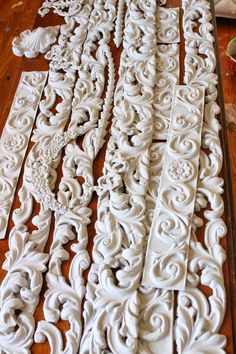 several pieces of carved white wood sitting on top of a wooden floor next to each other