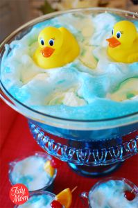 two rubber ducks in a bathtub filled with foamy water and blue bubbles on a table