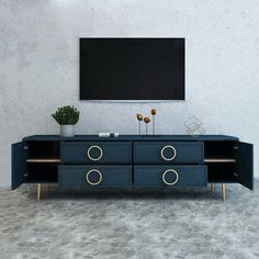 a tv is mounted on the wall above a blue cabinet with two gold handles and three round knobs