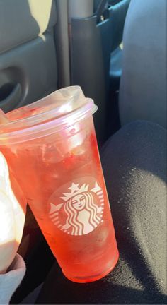 a starbucks cup sitting on the back seat of a car next to an orange drink