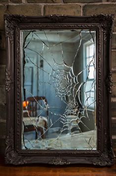 a mirror that has some kind of spider web on it in front of a brick wall