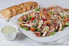 a white plate topped with a salad next to some baguettes and bread slices