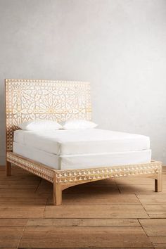 a bed that is sitting on top of a hard wood floor in front of a gray wall