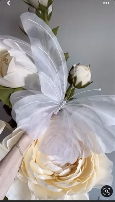 a white flower with a butterfly on it's wing next to a bouquet of flowers