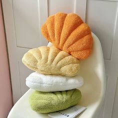 a stack of towels sitting on top of a white chair next to a book and an orange shell