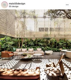 an outdoor living area with couches, tables and plants on the wall behind it