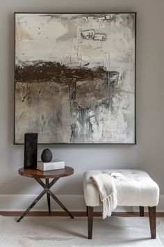 a painting hanging on the wall next to a small table with a book and vase