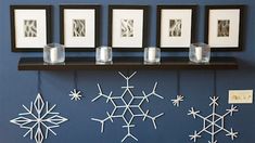 some snowflakes are hanging on the wall with pictures and candles in front of them