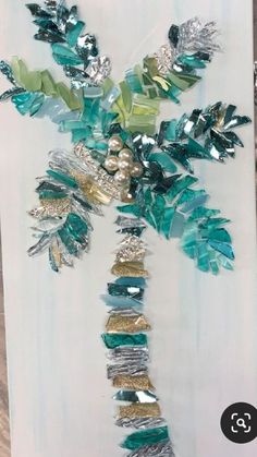 a palm tree made out of green and silver tinsels on a piece of white paper