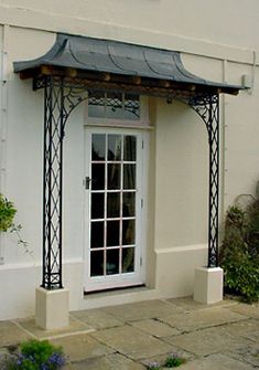 a white building with a black awning on the front door and side walk way