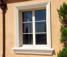 a cat sitting on the ledge of a window sill in front of a house