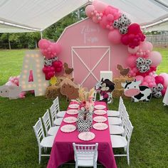 a table set up for a cow themed birthday party with balloons and farm animals on it