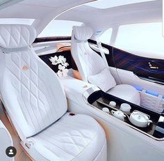 the interior of a luxury car with white leather seats and flowers in vases on the center console