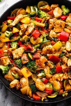 a skillet filled with chicken, peppers and broccoli