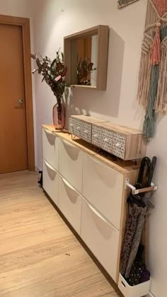 a white dresser sitting next to a wooden door in a room with wood flooring