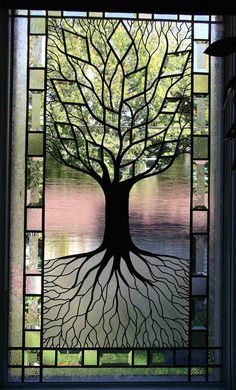 a stained glass window with a tree in the center and water behind it on a sunny day