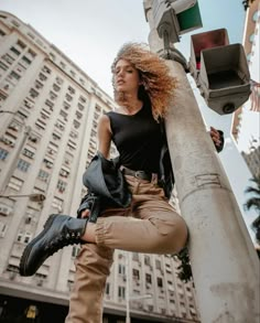 a woman standing on top of a pole next to a traffic light and tall buildings