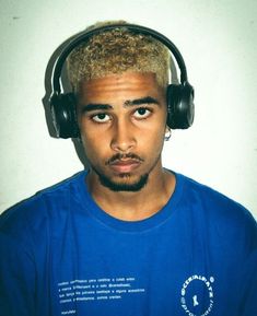 a man with headphones on his ears looking at the camera while wearing a blue t - shirt