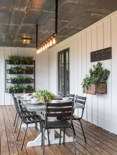 an outdoor dining area with wooden flooring and hanging planters on the wall above it