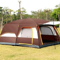 a brown and white tent sitting on top of a grass covered field next to trees