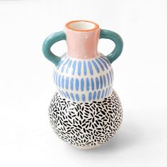 three ceramic vases sitting side by side on a white surface with blue and pink designs