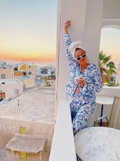 a woman in blue and white pajamas leaning against a wall with her hand on the side